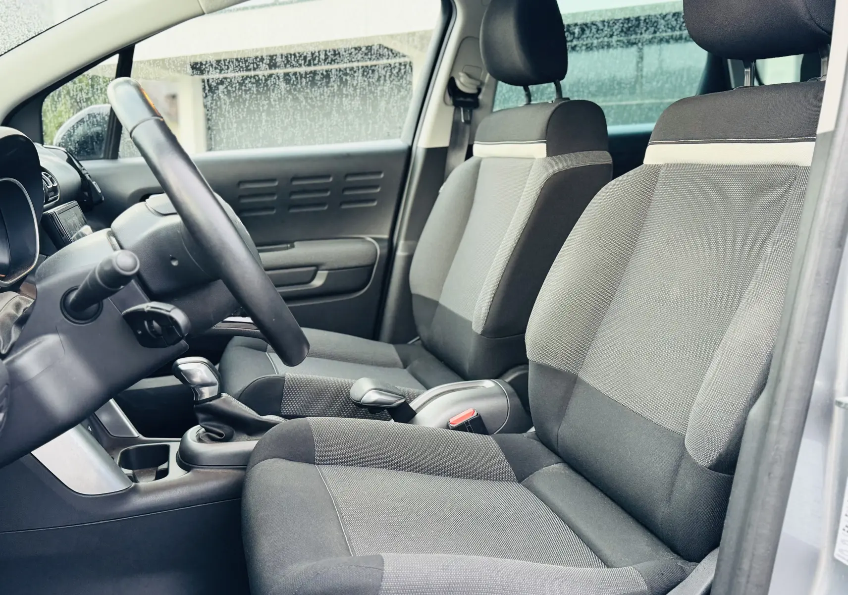 Vue intérieure côté gauche montrant les sièges avant en tissu gris Mica et le volant en croûte de cuir du Citroën C3 Aircross 2020.