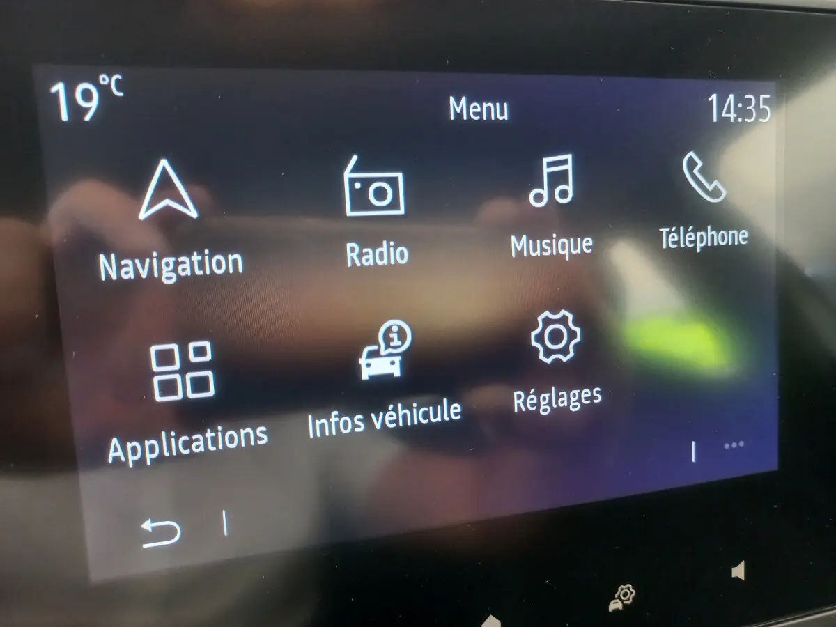 Écran tactile central de la Renault Clio Business blanc, affichant le menu principal avec navigation et radio.