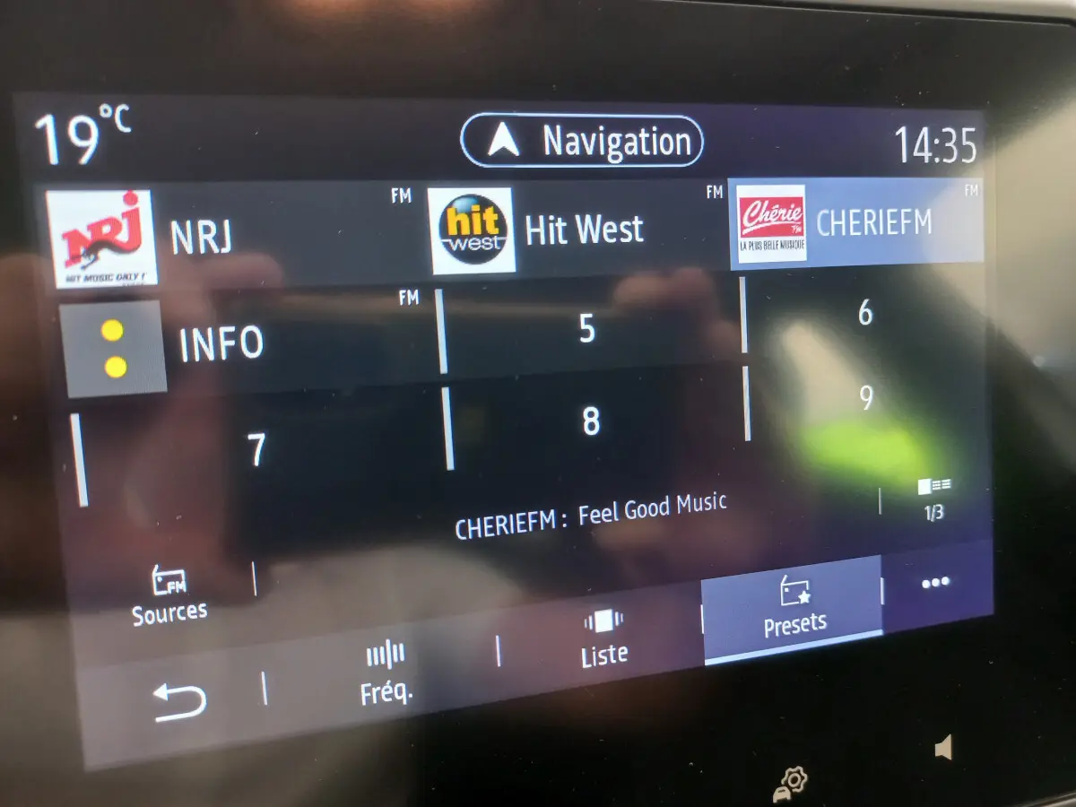 Écran tactile central de la Renault Clio Business blanc, affichant les stations radio FM et la navigation à 14h35.