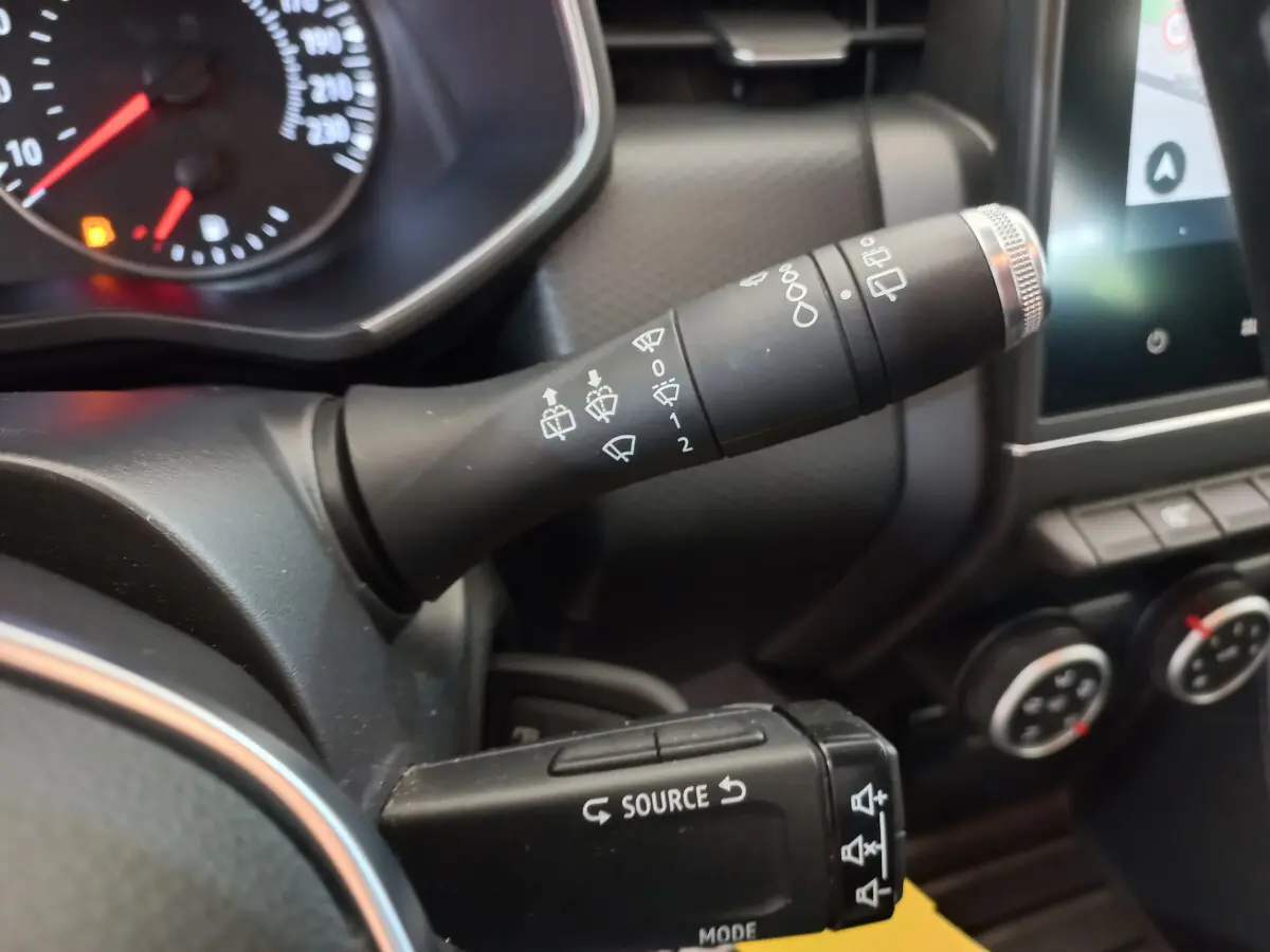 Gros plan sur les commandes au volant de la Renault Clio Business blanche, avec tableau de bord et écran tactile visibles.