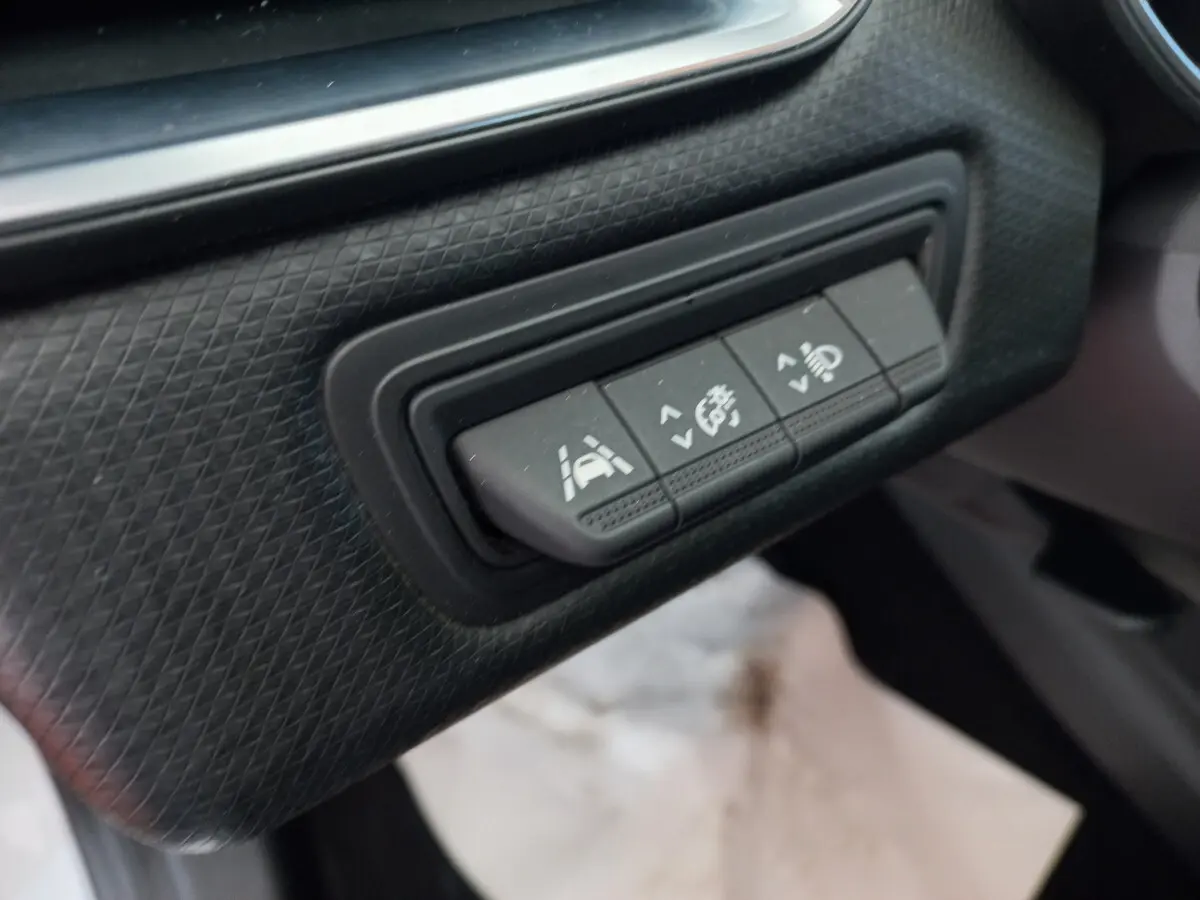 Gros plan sur les boutons de contrôle d'assistance à la conduite dans l'habitacle d'une Renault Clio Business blanche.