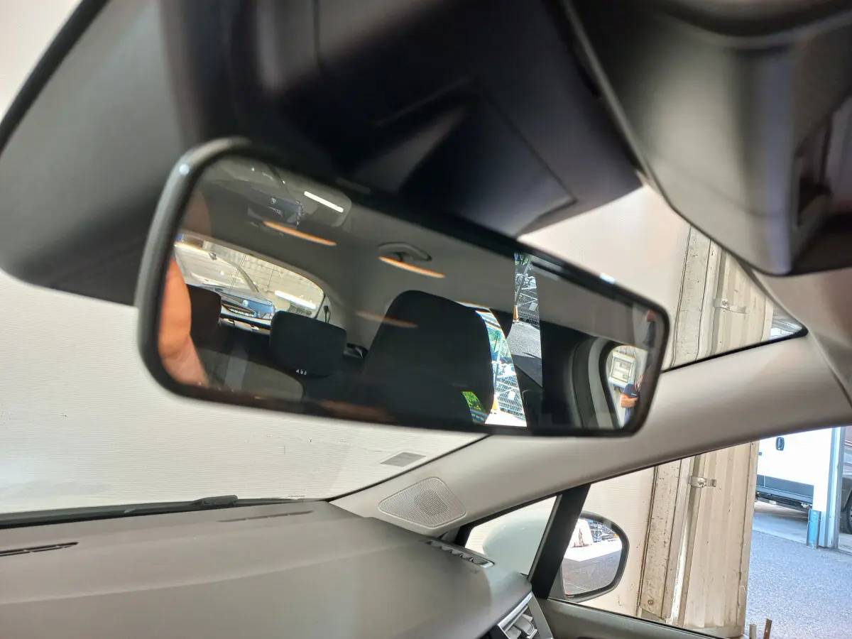 Vue intérieure du rétroviseur central d'une Renault Clio Business blanche, montrant l'arrière du véhicule et ses sièges noirs.