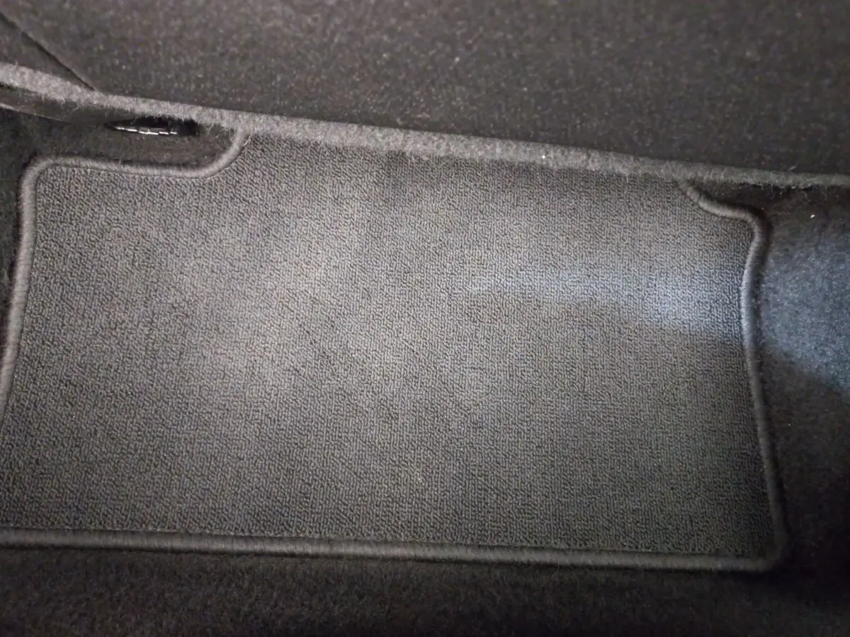 Tapis de sol noir en tissu dans l'habitacle d'une Renault Clio Business blanche, vue plongeante intérieure.