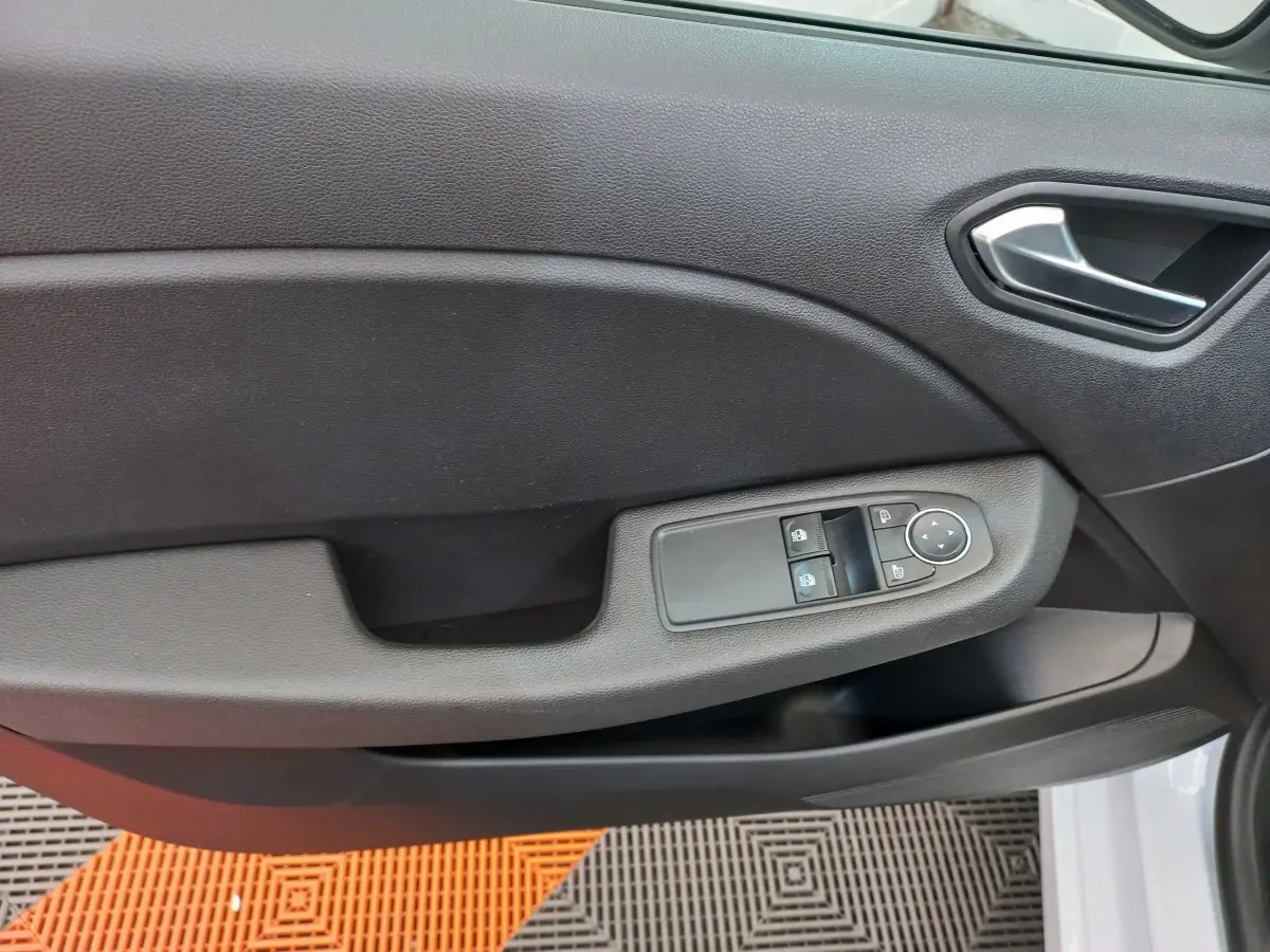 Poignée intérieure et panneau de porte côté conducteur en plastique noir de la Renault Clio Business blanche vue de près.