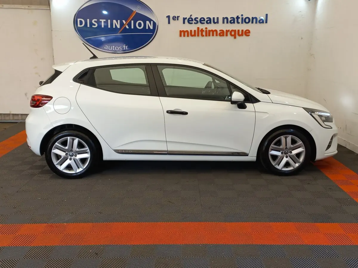 Profil côté gauche d'une Renault Clio Business blanche 2021, avec jantes alliage et poignées noires contrastantes.