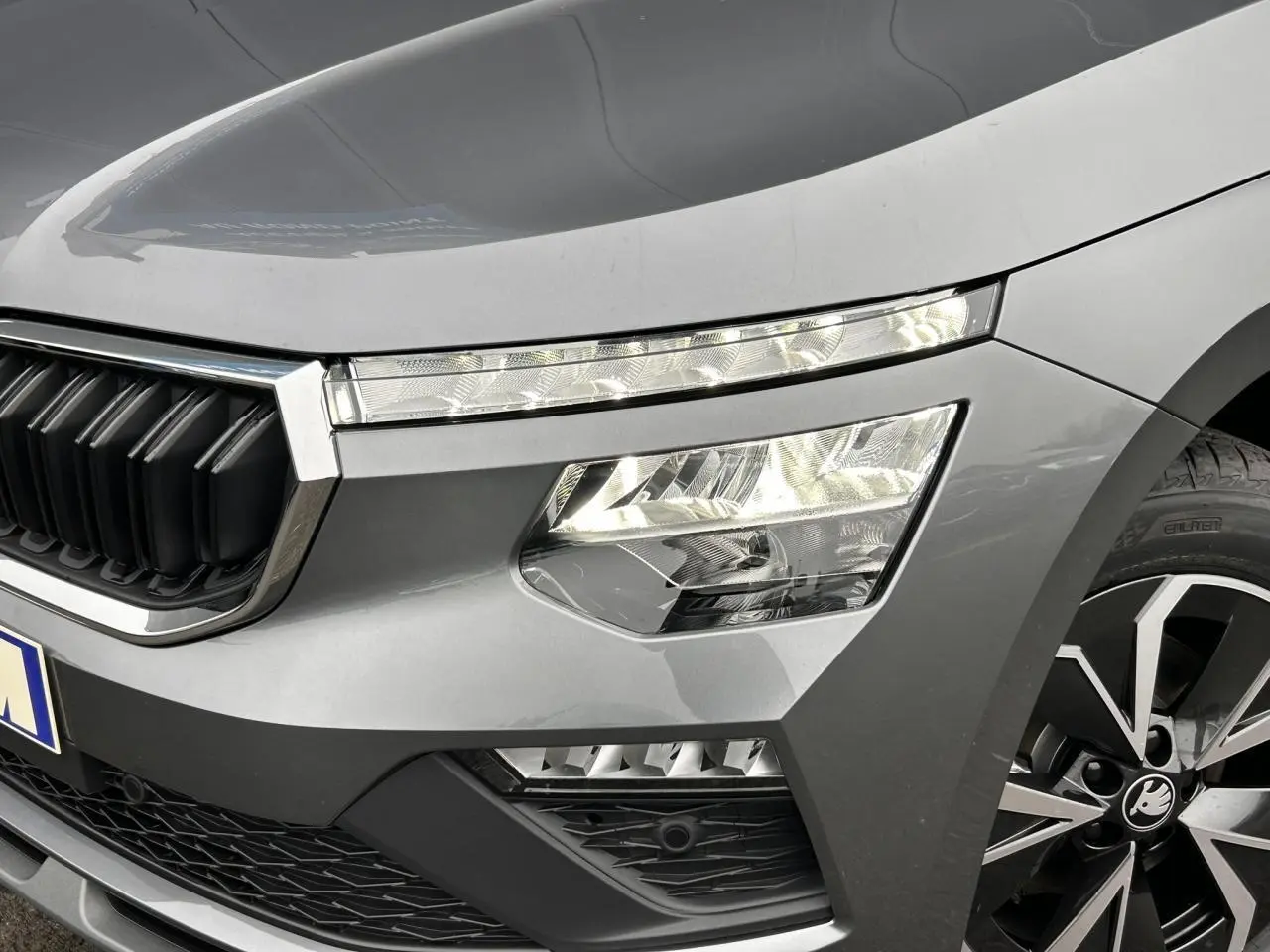 Gros plan sur l'avant droit du Skoda Kamiq gris graphite, mettant en valeur les phares Full LED et la calandre chromée.