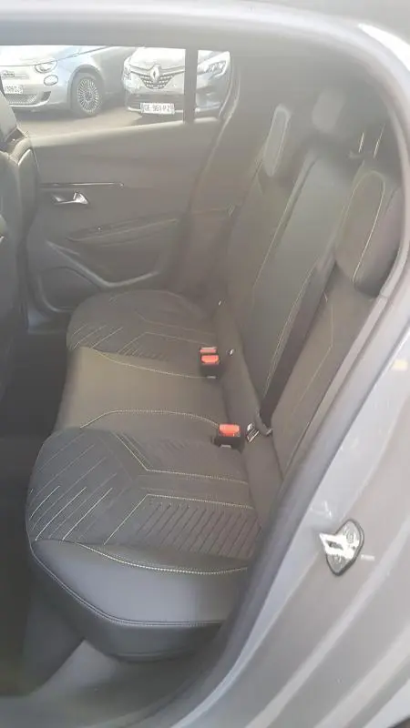 Vue intérieure côté gauche des sièges arrière en tissu et cuir gris d'une Peugeot 208 Hybrid 110 e-DCS6 GT 2025, avec ceinture rouge visible.