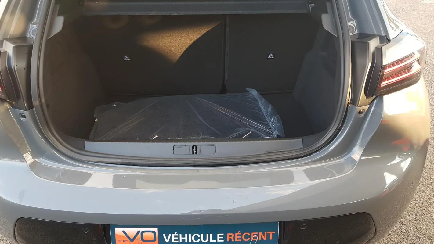 Coffre ouvert d’une Peugeot 208 gris 2025, vue arrière mettant en valeur l’espace de chargement et les feux arrière.