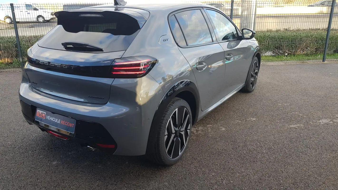 Vue 3/4 arrière droite d’une Peugeot 208 Hybrid 110 gris avec jantes alliage 17 pouces et feux LED distinctifs.