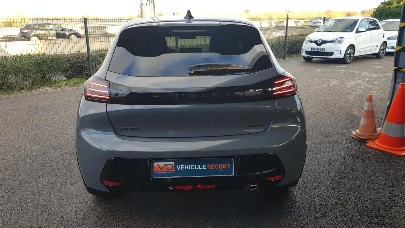 Vue arrière d’une Peugeot 208 Hybrid 110 gris métallisé avec feux LED allumés et jantes alliage 17 pouces.