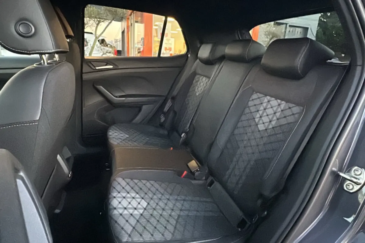 Vue intérieure arrière côté droit du Volkswagen T-Cross gris cendré, montrant la banquette arrière en tissu avec motifs géométriques.