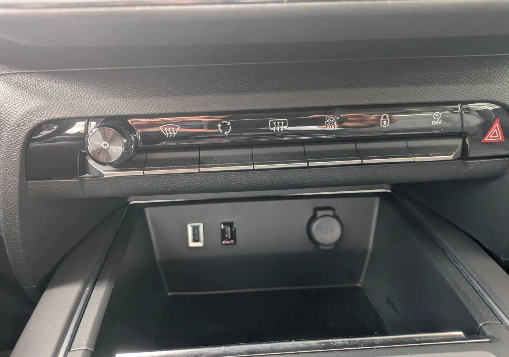 Vue rapprochée de la console centrale noire du Citroën C5 Aircross hybride 2025 avec commandes climatisation et ports USB.