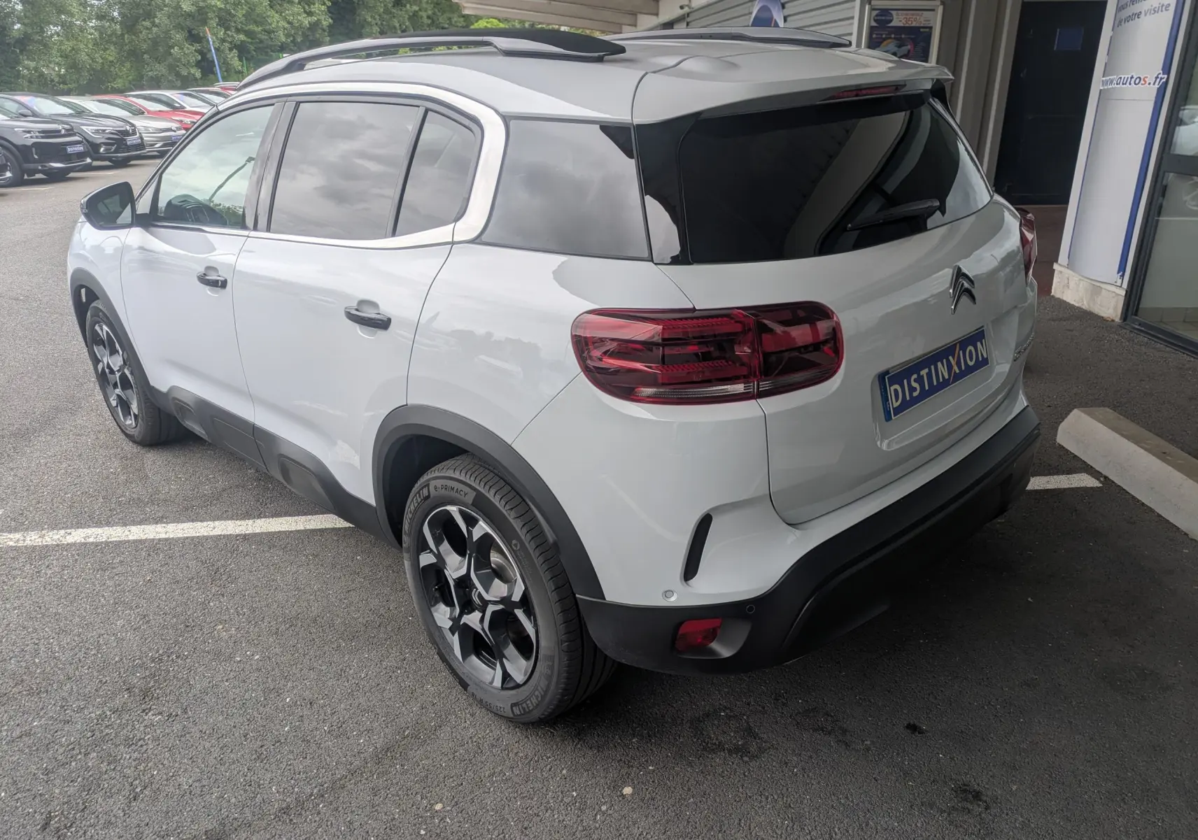 Vue 3/4 arrière droite d'un Citroën C5 Aircross hybride blanc Okenite avec jantes alliage biton et vitres arrière surteintées.