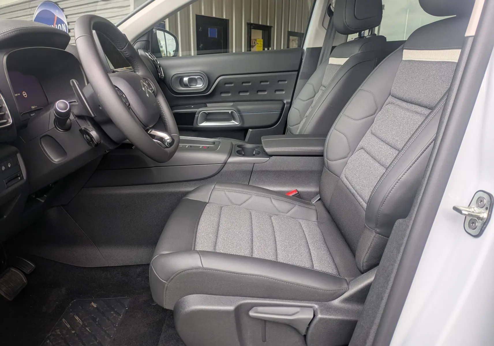 Vue intérieure côté conducteur du Citroën C5 Aircross hybride blanc Okenite, avec sièges tissu/TEP gris et volant cuir.