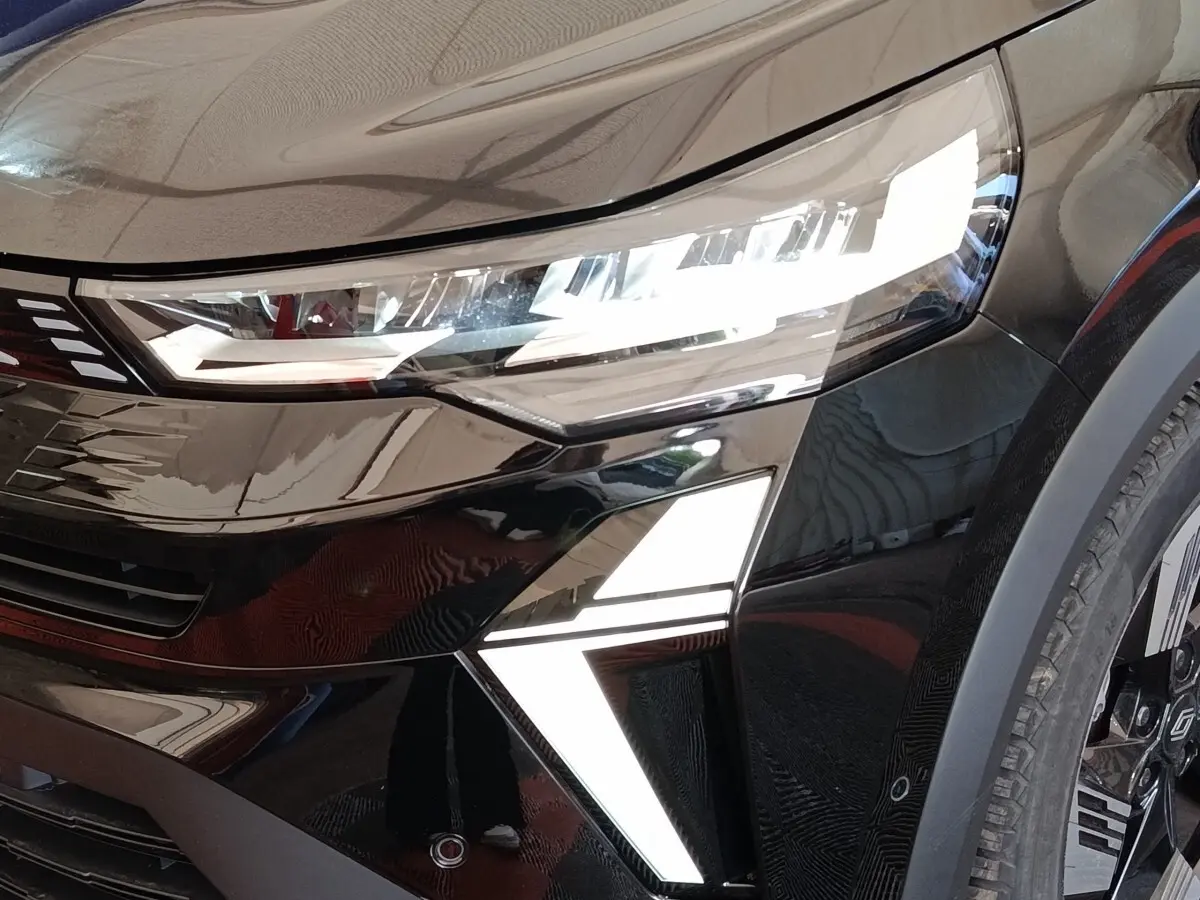 Gros plan sur l'avant droit noir brillant du Renault SYMBIOZ 2025 avec phares LED et feux diurnes en forme de flèche.