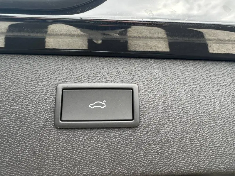 Gros plan sur le bouton d'ouverture électrique du coffre, entouré de garniture noire texturée, intérieur du CUPRA Formentor noir.