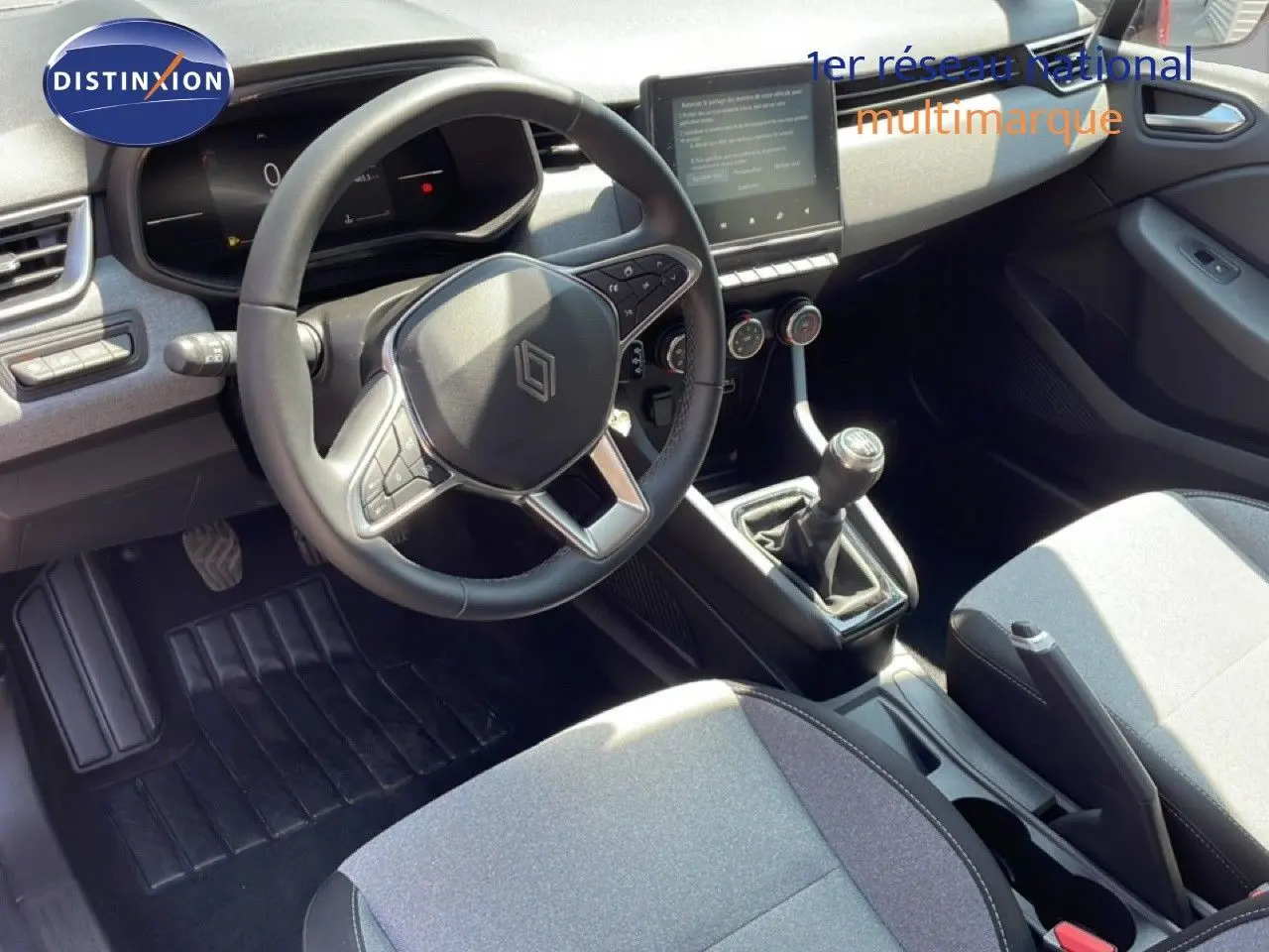 Vue intérieure de la Renault Clio V BluedCi 100ch Evolution 2025, montrant le volant cuir, la boîte manuelle et l’écran tactile central.