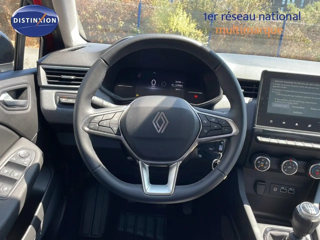 Vue intérieure centrée sur le volant cuir de la Renault Clio 2025, avec tableau de bord digital et console centrale moderne.