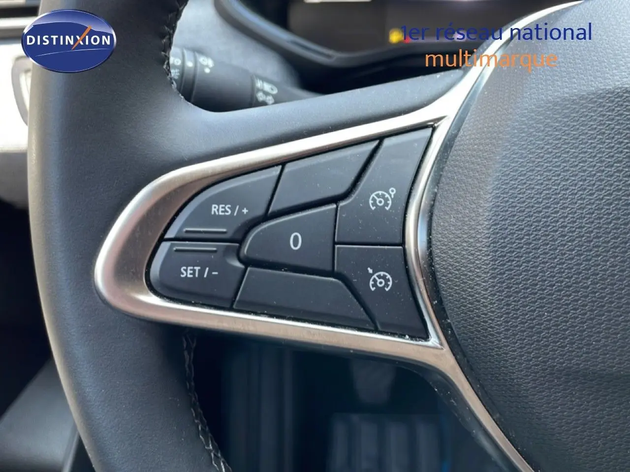 Gros plan sur les commandes de régulateur de vitesse au volant d’une Renault Clio rouge flamme métal, version 2025.