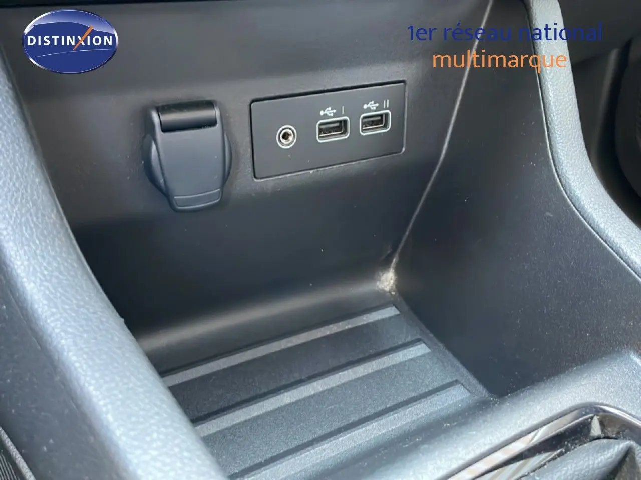 Gros plan sur la console centrale noire de la Renault Clio, montrant deux ports USB et une prise auxiliaire.