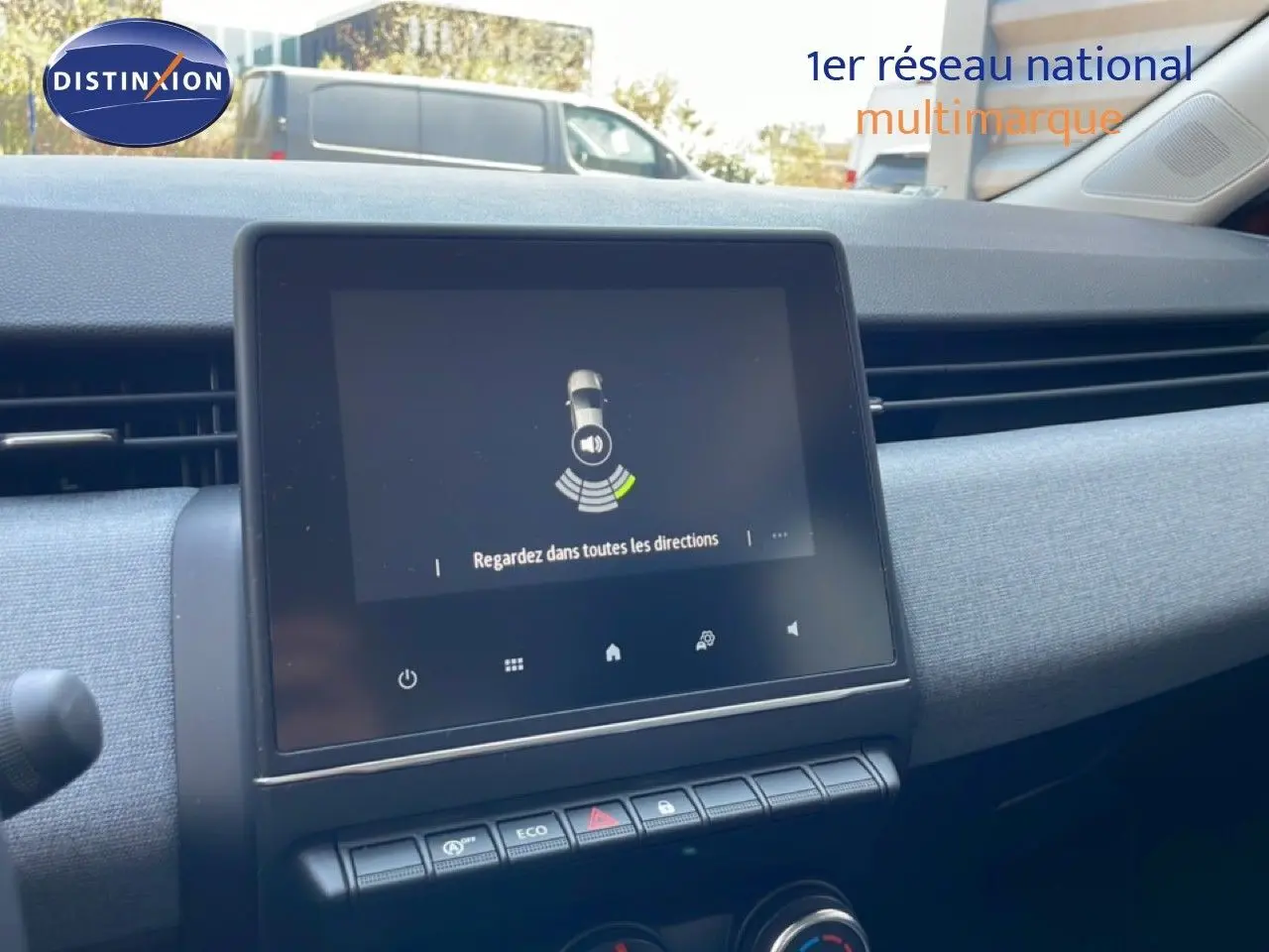 Vue rapprochée de l’écran tactile central et de la planche de bord grise intérieure d’une Renault Clio rouge flamme 2025.