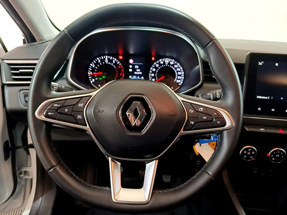 Vue rapprochée du volant en cuir noir de la Renault Clio Business 2021 avec tableau de bord et écran tactile visible.