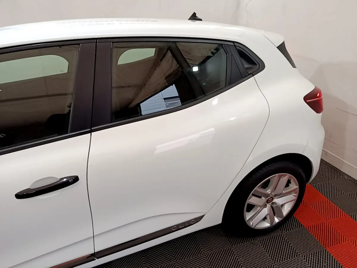 Vue côté gauche arrière d'une Renault Clio blanche avec poignées noires et jantes alliage argentées.