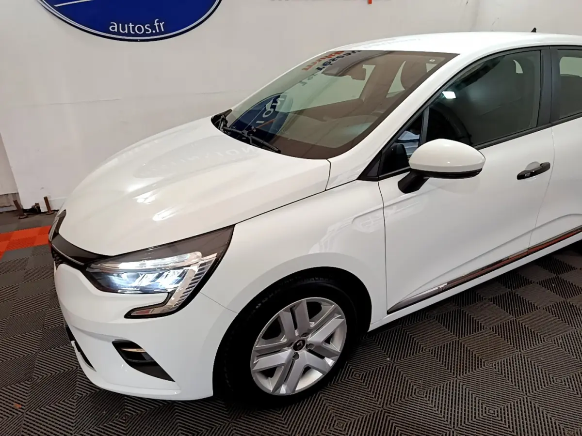 Renault Clio Business blanche vue de 3/4 avant droit, avec phares LED allumés et jantes alliage visibles.