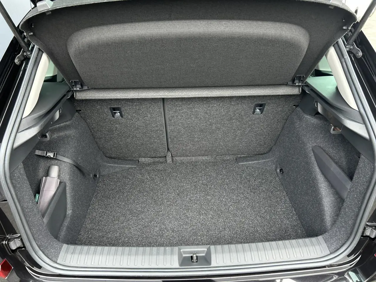 Coffre ouvert vu de l'arrière d'un Skoda Kamiq noir Magic, intérieur de coffre propre et spacieux.