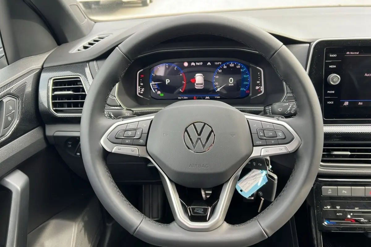Vue centrée du volant cuir multifonctions avec logo Volkswagen et tableau de bord digital du T-Cross TSI 116 DSG7 R-Line 2025.