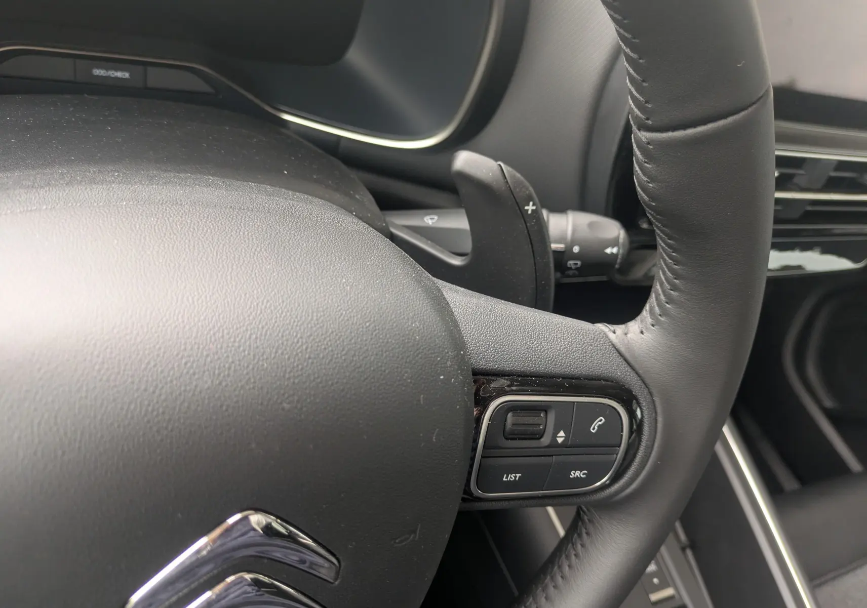 Gros plan sur le volant en cuir noir du Citroën C5 Aircross hybride 2025, avec commandes intégrées côté droit.