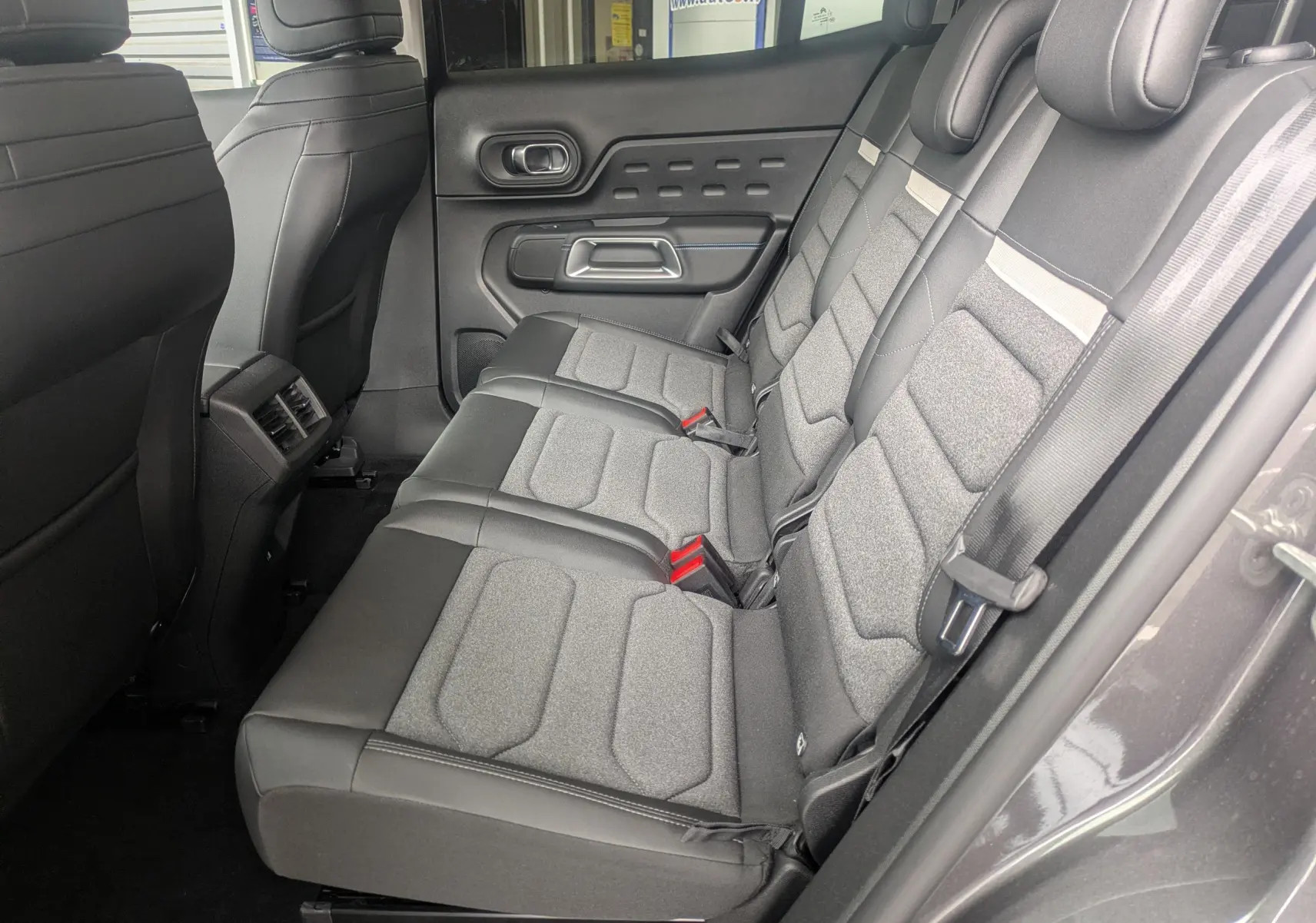 Vue intérieure côté droit des sièges arrière gris tissu et TEP du Citroën C5 Aircross Hybride 2025 avec porte ouverte.
