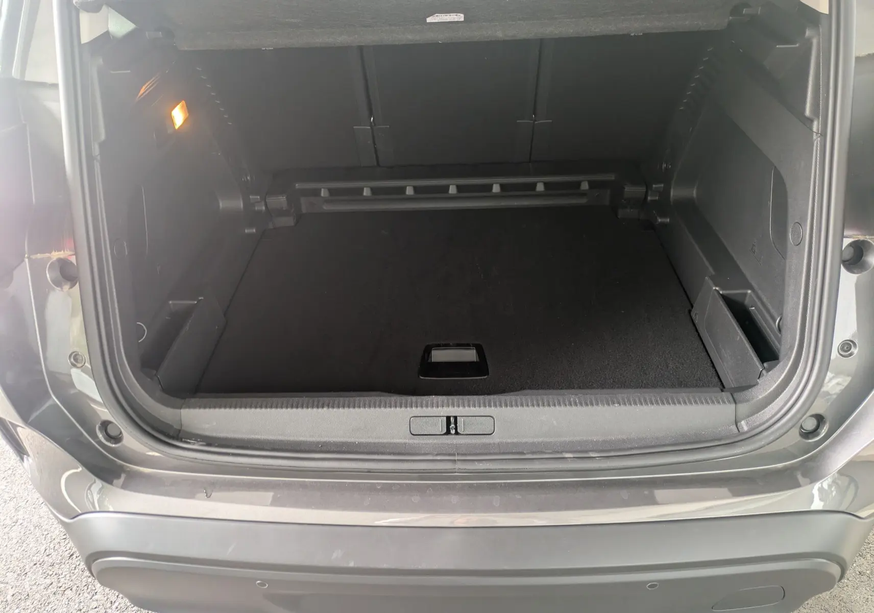 Coffre ouvert vu de l'arrière du Citroën C5 Aircross hybride gris platinium, montrant l'espace de chargement vide.