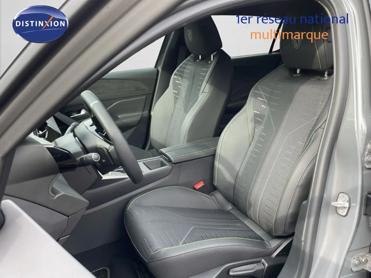 Vue intérieure côté conducteur de la Peugeot 308 gris selenium, sièges sport en tissu et cuir avec surpiqûres vertes.