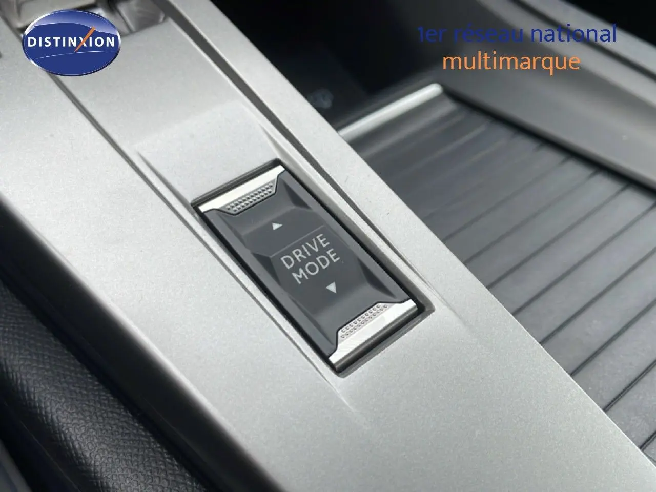 Gros plan sur le bouton Drive Mode gris argenté au centre de la console intérieure de la Peugeot 308 1.2 Hybrid 145ch GT 2026.