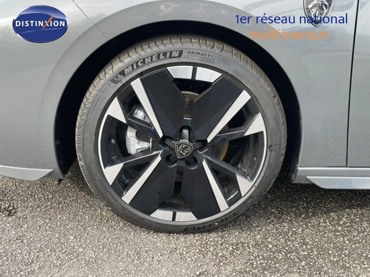 Gros plan sur la roue avant gauche de la Peugeot 308 gris selenium métal, mettant en valeur la jante noire et argentée au design moderne.