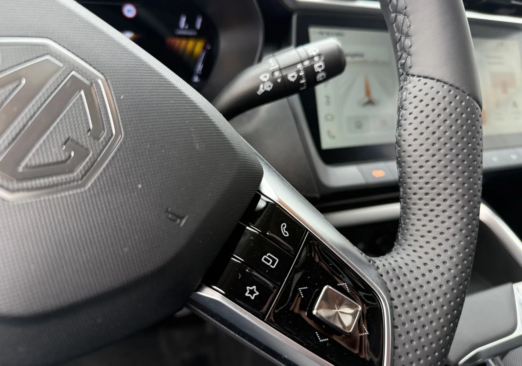Gros plan sur le volant perforé noir du MG ZS 1.5 HYBRID+ 197 LUXURY avec commandes intégrées et tableau de bord numérique.