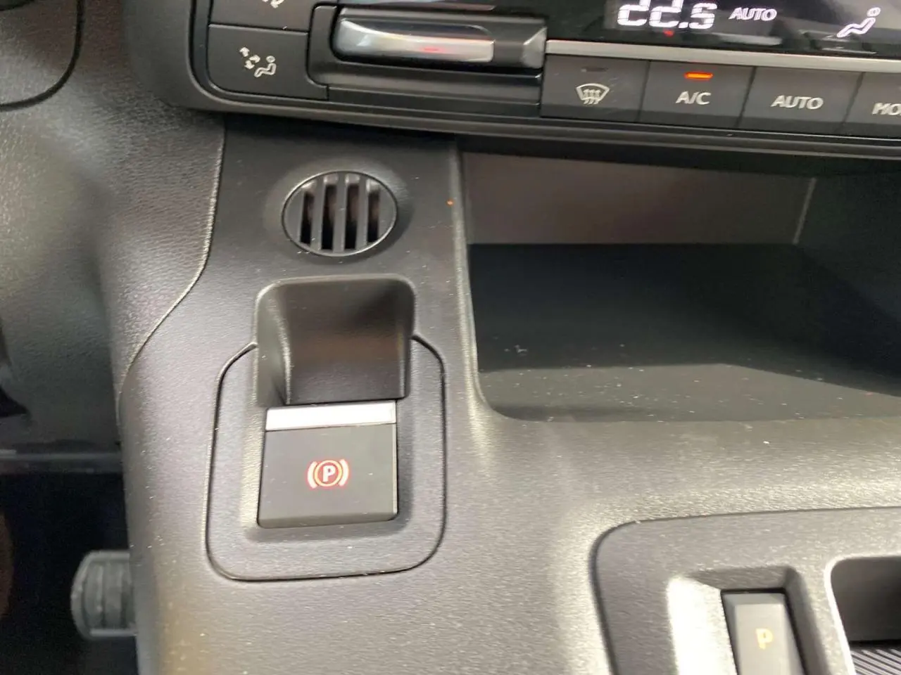 Gros plan sur la console centrale du Citroën Berlingo Multispace blanc 2025, montrant le frein à main électrique et commandes climatisation.