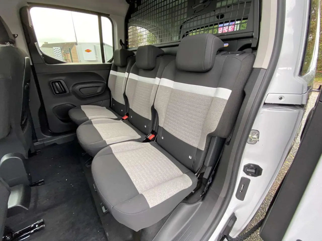 Vue intérieure côté droit des sièges arrière gris et noirs du Citroën Berlingo Multispace blanc 2025 avec séparation grillagée.