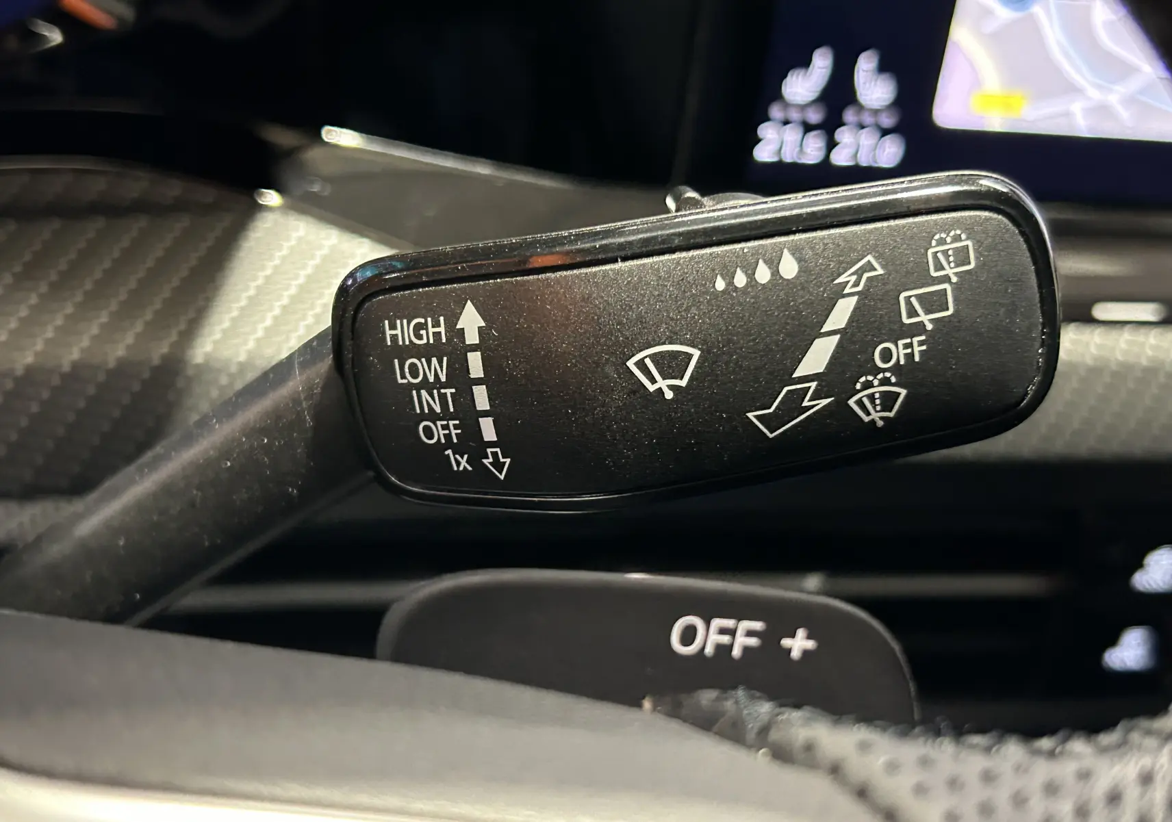 Gros plan sur la commande des essuie-glaces dans l’habitacle d’une Volkswagen Golf VIII eTSI noire, affichage digital en arrière-plan.