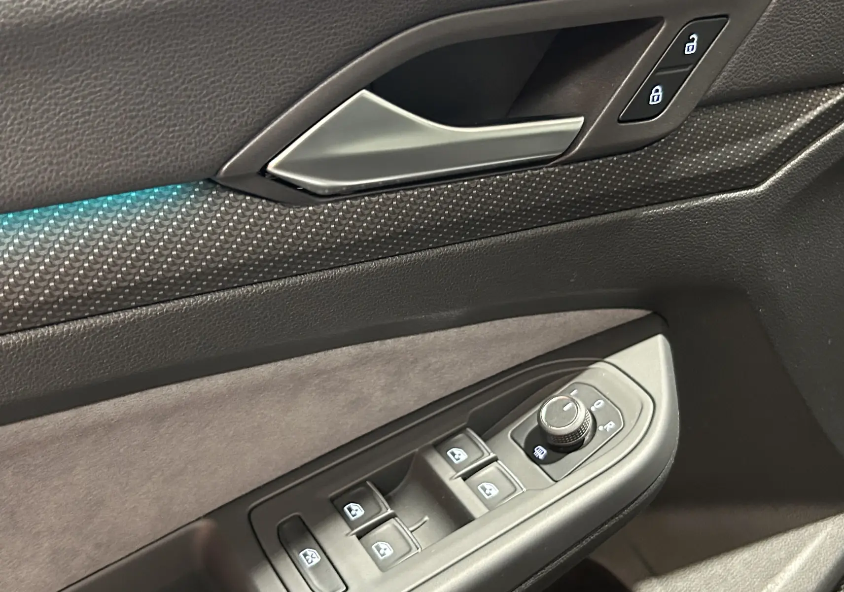 Détail de la porte côté conducteur de la Volkswagen Golf VIII eTSI noire, montrant les commandes de vitres et de rétroviseurs.