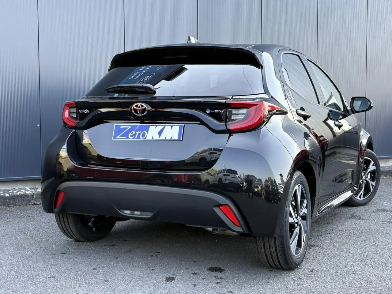 Toyota Yaris Hybride noire vue 3/4 arrière droit, avec feux LED et jantes alliage 16 pouces visibles.