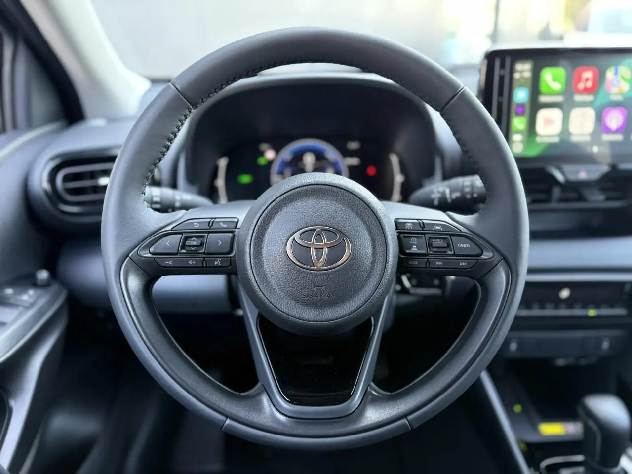 Vue centrée sur le volant cuir noir de la Toyota Yaris 2025 hybride avec tableau de bord numérique et écran tactile connecté.