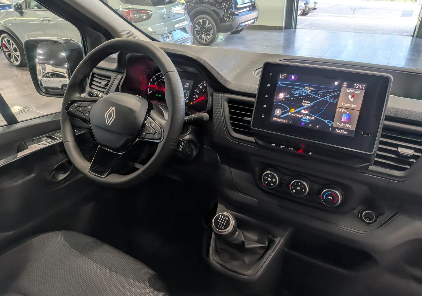 Vue intérieure côté conducteur du Renault Trafic Combi 2025, tableau de bord noir avec écran tactile et levier de vitesses manuel.