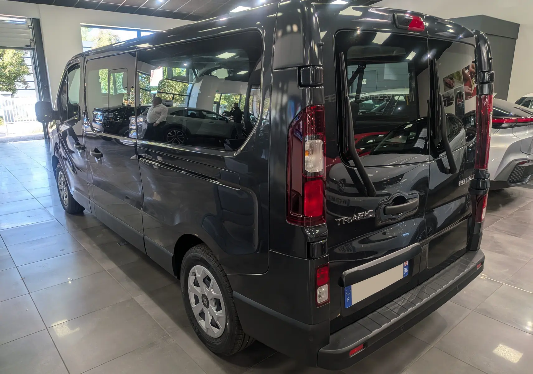 Vue 3/4 arrière droite du Renault Trafic Combi gris Comète avec porte arrière équipée d'une rampe d'accès TPMR.