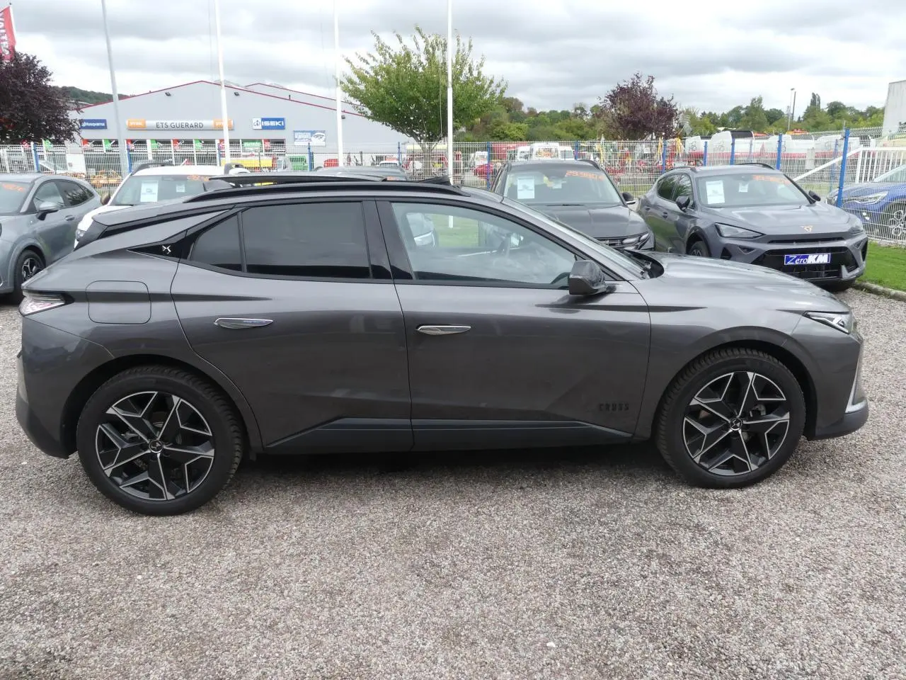 Profil côté gauche d'une DS4 Cross Rivoli gris métallisé avec jantes alliage 19 pouces sur parking extérieur.