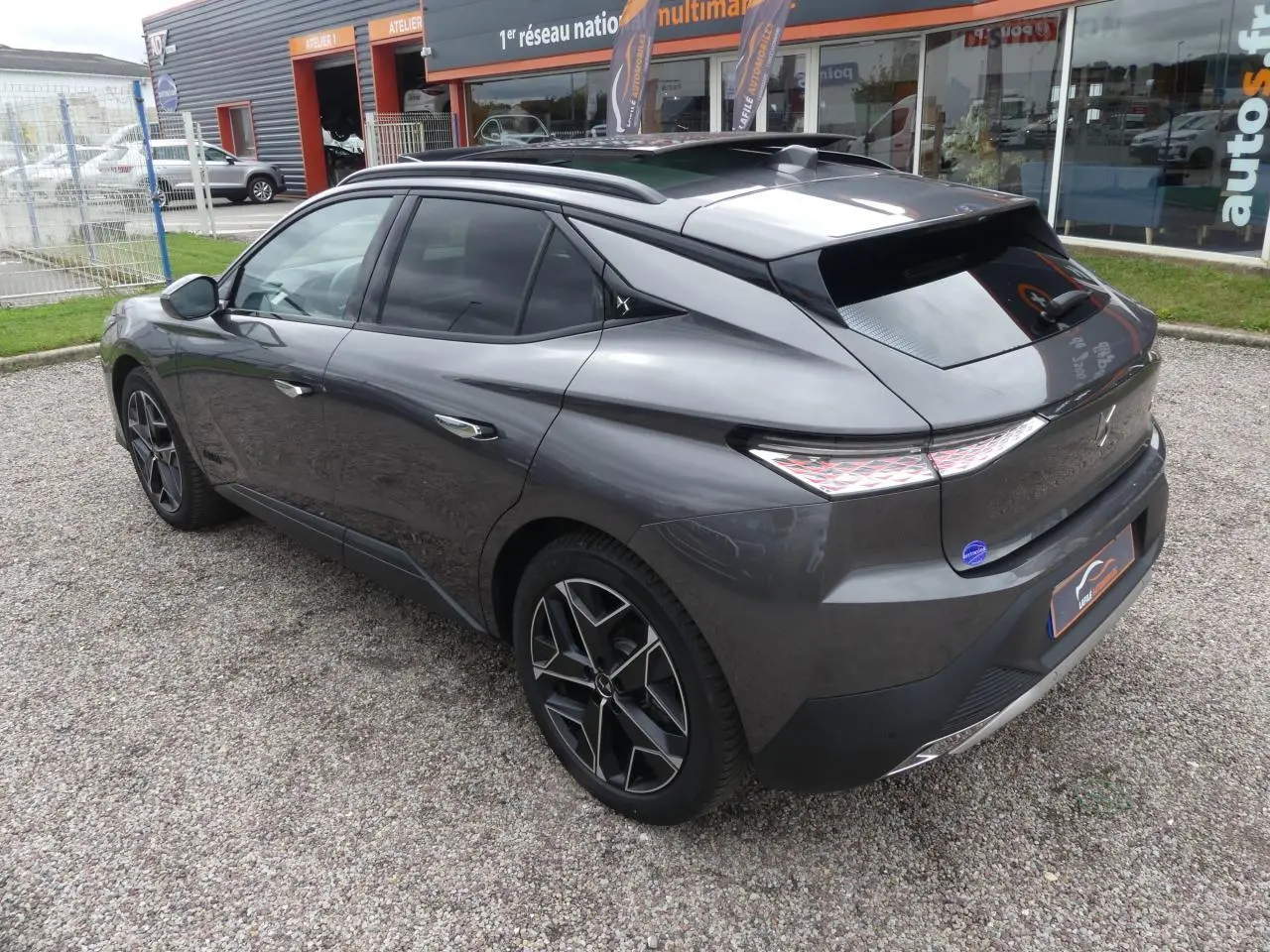 DS4 gris métallisé vu en 3/4 arrière côté gauche, avec jantes alliage noires et toit ouvrant électrique.