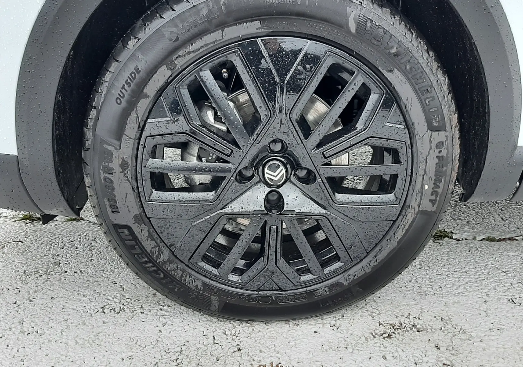 Gros plan sur la roue avant droite d'une Citroën C4 blanche, jante noire au design géométrique distinctif.