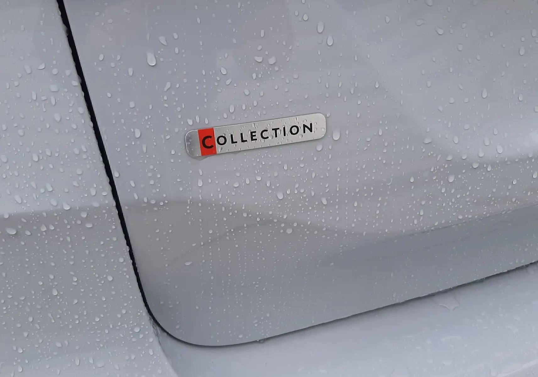 Gros plan sur l’écusson "Collection" sur la porte blanche du côté gauche d’une Citroën C4 hybride.