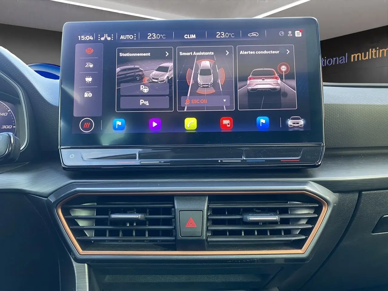 Vue rapprochée de l’écran tactile central et des aérateurs du tableau de bord intérieur d’une CUPRA Leon 2023 noire.